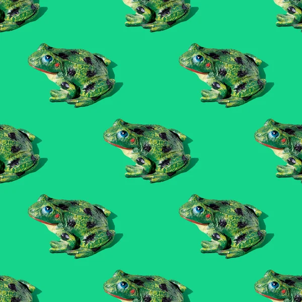 Seamless pattern from frog statue on green background with shadows