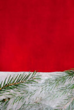 Sprigs of a Christmas tree frozen in block of ice on a red velvet background. Minimal winter holidays concept. Copy space. Space for text. Sustainable Holidays