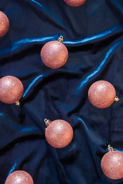 Peach color glittery christmas decoration balls on a blue velor background. Christmas party aesthetic wallpaper