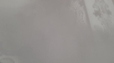 Perdelerin çözünmüş gölgeleri rüzgarlı bir havada hareket eden gri arka plana düşer. Yaşayan duvar kâğıdı. Gölge ve ışıkla soyut bir bakış açısı. Dramatik ya da sinematik video.