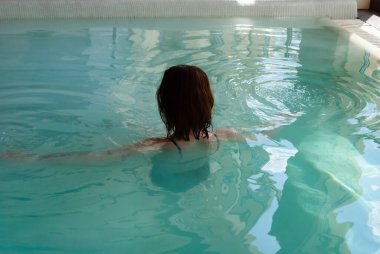 Tuzlu su havuzunda kısa saç stili olan Millennials 'lı kadın kameraya arkasını döndü. Tuz havuzu küçük oksijen molekülleriyle dolu. Kan dolaşımını ve metabolizmayı uyaran, mineral besinleriyle zenginleştiren bir prosedür. Tıbbi Turizm