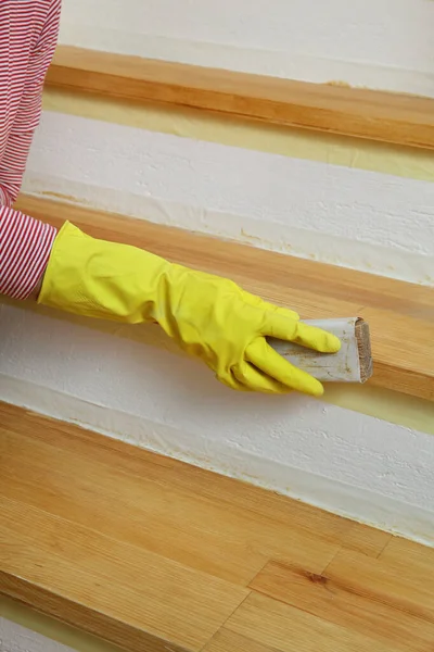Worker sanding plank at stairs using sand paper