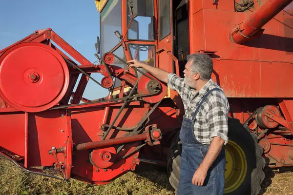 Adult Farmer Mechanic Touching Examining Belt Combine Harvester Stock Photo