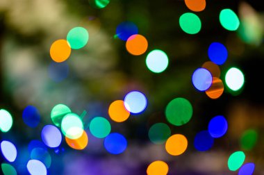 Odaklanmamış renkli ışıklarla dolu bir arka plan. Bulanık ışık izleri ve noel ağacı lekeleri.