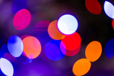 Odaklanmamış renkli ışıklarla dolu bir arka plan. Bulanık ışık izleri ve noel ağacı lekeleri.