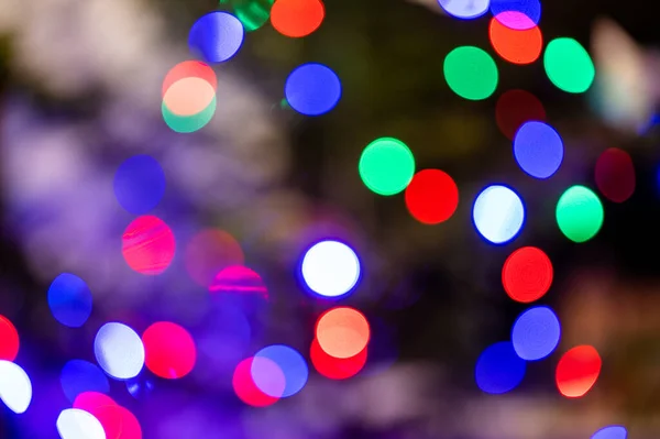 Background full of an unfocused colorful lights. Blurred lights traces and spots of Christmas tree.