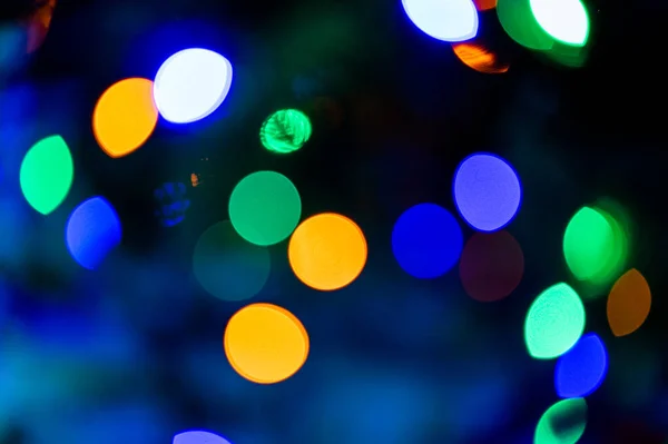 Background full of an unfocused colorful lights. Blurred lights traces and spots of Christmas tree.