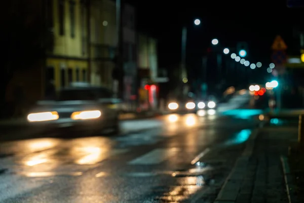 City street night blurred background. Cars approaching a pedestrian crossing. Bokeh night city life. The city of Ustzyki Dolne, Poland.