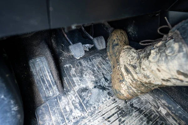 Close-up of a man\'s legs in military camouflage with trekking boots soiled in mud in the car