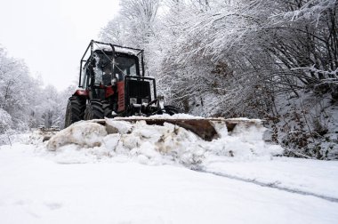 A tractor shoveling snow from a mountain road in the Carpathians, Poland.