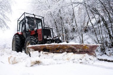 A tractor shoveling snow from a mountain road in the Carpathians, Poland.