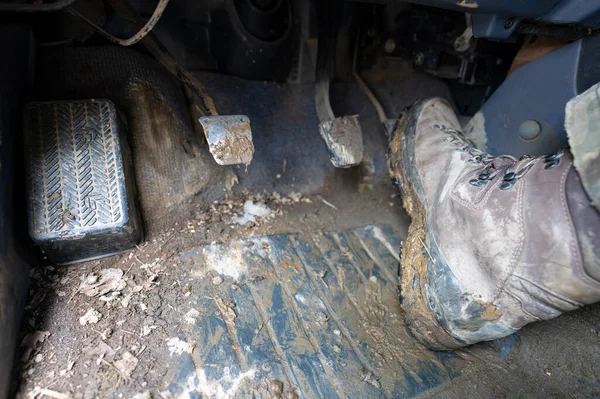 Close-up of a man\'s legs in military camouflage with trekking boots soiled in mud in the car.
