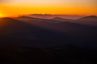 Güneş doğarken turuncu gökyüzü ile dağların karanlık siluetleri. Fotokopi alanı olan karanlık bir arkaplan. Parang Dağları, Romanya.