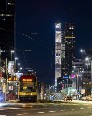 Varşova, Polonya - 26 Aralık 2023: Şehir ışıklarıyla çevrili Tytusa Chalubinski caddesinde bir tramvay. Varşova şehir merkezinin gece manzarası.