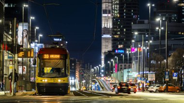 Varşova, Polonya - 26 Aralık 2023: Şehir ışıklarıyla çevrili Tytusa Chalubinski caddesinde bir tramvay. Varşova şehir merkezinin gece manzarası.