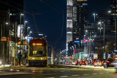 Varşova, Polonya - 26 Aralık 2023: Şehir ışıklarıyla çevrili Tytusa Chalubinski caddesinde bir tramvay. Varşova şehir merkezinin gece manzarası.