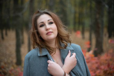 Sonbahar ormanında montlu bir kız. Parkta yürüyen kızıl saçlı kadın. Beyaz çizmeler. Güzel bir kadının yakın portresi