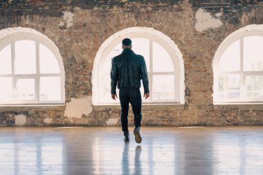 Büyük pencerenin önünde deri dövmeli seksi adam. Yakışıklı, genç, atletik erkek model. Çıplak gövdeli kaslı, seksi erkek. Dövmeli, acımasız, yakışıklı bir adam..