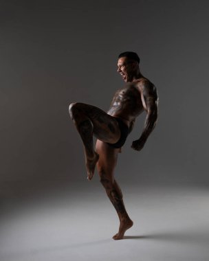 Güzel karın kasları olan genç kaslı adam. Hareketli bir dövüşçü. Dövmeli kickboksör. Dövüş sanatları eğitimi almış. Vücut geliştirme. Stüdyoda poz veren seksi bir adam.