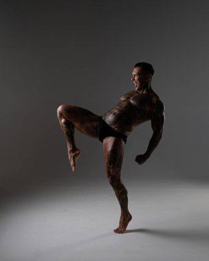 Güzel karın kasları olan genç kaslı adam. Hareketli bir dövüşçü. Dövmeli kickboksör. Dövüş sanatları eğitimi almış. Vücut geliştirme. Stüdyoda poz veren seksi bir adam.