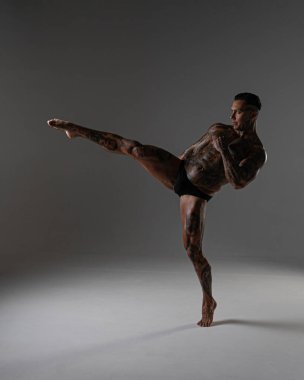 Güzel karın kasları olan genç kaslı adam. Hareketli bir dövüşçü. Dövmeli kickboksör. Dövüş sanatları eğitimi almış. Vücut geliştirme. Stüdyoda poz veren seksi bir adam.