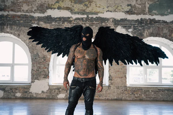 Male angel with black wings. Black angel in a mask. Muscular shirtless man with whip in a mask.Brutal handsome man with tattooed body. Muscular athletic sexy male with naked torso. hot man