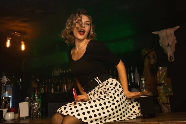 Portrait of beautiful happy woman dressed in pin-up style in a white dress in polka dot. Caucasian blond model posing in retro fashion and vintage concept . hot girl in a bar with lollipop