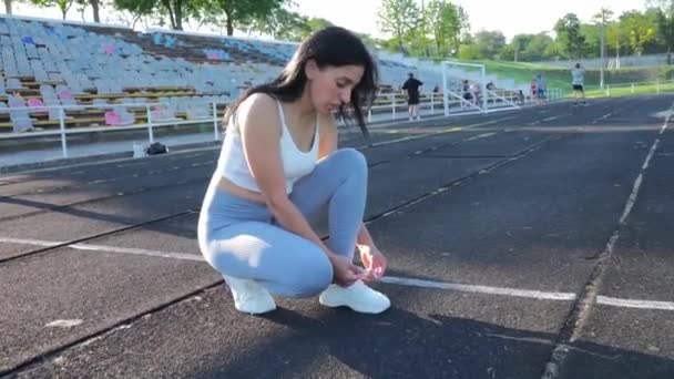 彼女はランニング場で彼女の靴ひもを結び競技会の準備をしていた スポーティーなライフスタイル 運動トレーニングの準備 スタジアムのスポーツ女子 — ストック動画