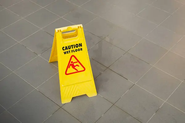 Yellow Caution Slippery Wet Floor Sign Showing and Warning of Caution Wet Floor on the Walk Way.