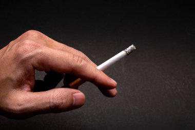Bir adamın eli, sigara içme eylemine kendini kaptırmış, kendini yaralayan kişinin esenliğine dokunaklı bir resim çizer.