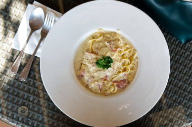 Yemek masasında servis edilen taze hazırlanmış ve lezzetli bir Carbonara spagettisi..