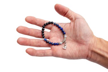Doğal taş boncuklardan yapılmış bir bilezik. Adamın elinde elmas bir kolye var. İzole edilmiş beyaz arka planda..