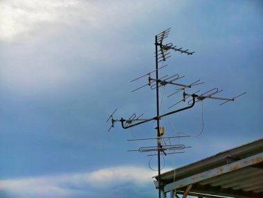 Çatıdaki gökyüzünde eski bir teknoloji TV anteni, çocukluk anılarını anımsatan nostaljik bir teknoloji..