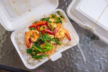 Popüler kızarmış fesleğen karidesi sıcak pirinçle servis edilir. Çevre dostu bir karton kutuda. Yemek masasında nefis yapılmış bir yemek..