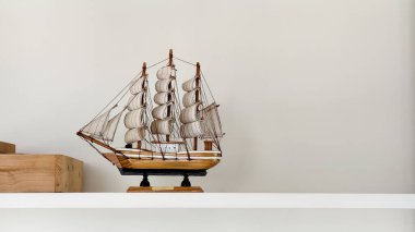 Süslü ahşap yelkenli gemi modeli beyaz bir rafta sergileniyor. Denizcilik, klasik ve asgari ev dekorasyonu için mükemmel. Seyahat, macera, denizcilik, tarih ve minimalist yaşam tarzı temaları için ideal stok fotoğrafı