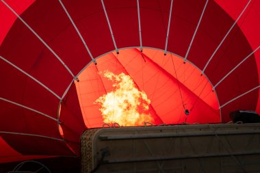Kırmızı bir sıcak hava balonunu şişiren yanan bir gaz jeti.