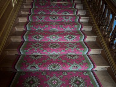 Kırmızı desenli halısı olan tahta merdiven.