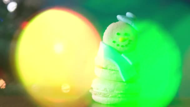Снеговик Десерт Макарон Украшен Шляпой Шарфом Красочными Огнями Боке Мигает — стоковое видео