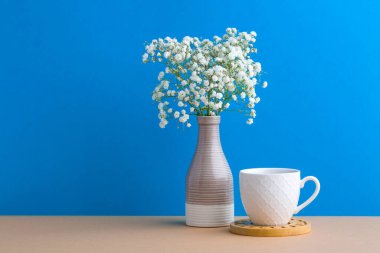 Modern vazodaki güzel küçük beyaz çiçekler ahşap masa arkasındaki arka planda fotokopi alanı, yumuşak bir tonu ve durgun bir hayatı var.