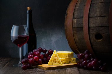 Red wine in low light with cheese and grape,wine barrel and glass,still life