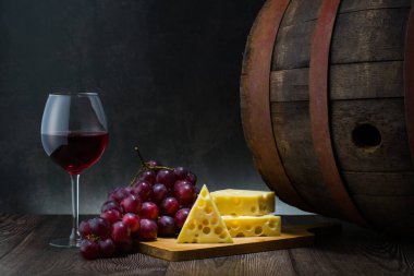 Red wine in low light with cheese and grape,wine barrel and glass,still life