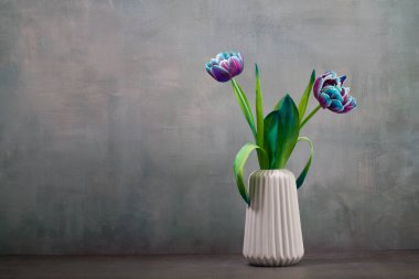 Fresh colorful tulips flowers in vase on rustic green wall Place for your text,copy space