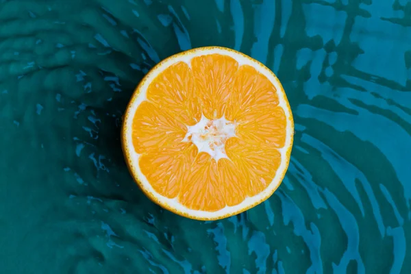 orange fruits in green water background with concentric circles and ripples. Refreshing summer concept,closeup