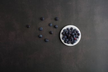blueberryTop view of blueberries in a bowl on dark background with copy space.