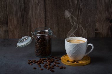 White espresso cup and coffee beans dark table background with copy space. Arabica grains, Coffee shop, caffeine, roast concept