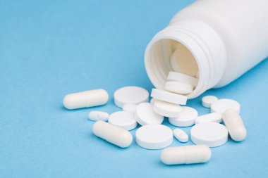 İlaç şişesinden dökülen beyaz ilaç tabletleri ve haplar. Kopyalama alanı olan yukarıdan aşağıya görünüm.