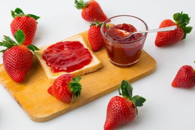 Beyaz bir arka planda çilek reçelli ekmek ve çilek meyvesinin kuş bakışı görüntüsü