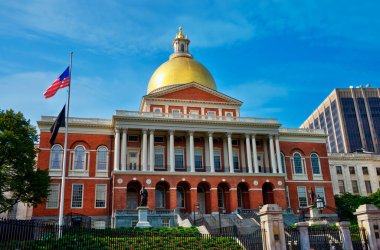 Boston, Massachusetts - ABD - 2023-30-07 Massachusetts Eyalet Binası ikonik altın kubbesi ve açık bir yaz gününde dalgalanan Amerikan bayrağıyla. Tarihi bir hükümet binası ve önemli bir şehir simgesi..