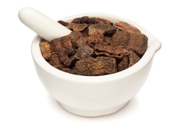 Beyaz zemin üzerinde izole edilmiş, beyaz seramik havan ve topuz meyveleri, Kuru Shikakai (Acacia concinna) yakın plan.