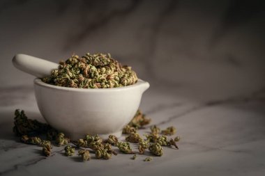 Dry Sanjivini Booti 'nin (Selaginella bryopteris) beyaz seramik havan ve tokmak yaprakları. Marbel arkaplanda ön görünüm.